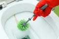 Hands in red gloves cleaning WC, toilet, using brush. Limescale. Hard water. Cleaning toilet bowl with limescale using detergent. Royalty Free Stock Photo
