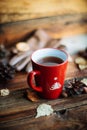 Hands in red knitted gloves holding a hot cup of coffee against yellow leaves background. Concept of autumn time, warmth and cozin Royalty Free Stock Photo