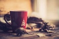 Hands in red knitted gloves holding a hot cup of coffee against yellow leaves background. Concept of autumn time, warmth and cozin Royalty Free Stock Photo