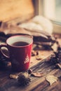 Hands in red knitted gloves holding a hot cup of coffee against yellow leaves background. Concept of autumn time, warmth and cozin Royalty Free Stock Photo