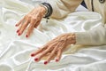 Hands with red nails on white silk. Royalty Free Stock Photo