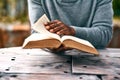 Hands, religion and a man reading the bible at a table outdoor in the park for faith or belief in god. Book, story and Royalty Free Stock Photo