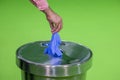 Hands remove glove on green background and dump into trash can. The concept of treatme Royalty Free Stock Photo