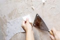Hands remove old wallpaper from the wall with a spatula during repair in the room