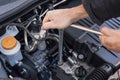 Hands repairing a car engine with a wrench