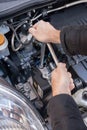 Hands repairing a car engine with a wrench