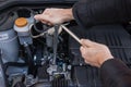 Hands repairing a car engine with a wrench