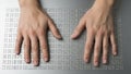 Hands resting on braille textured surface with raised dots fingers Royalty Free Stock Photo