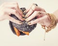 Hands of rich woman with golden manicure and jewelry holding black hamburger close up Royalty Free Stock Photo