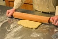 Shortcrust pastry rolled on a metal board with a wooden rolling pin