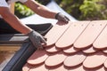 Hands of roofer laying tile on the roof. Installing natural red tile