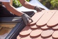 Hands of roofer laying tile on the roof. Installing natural red tile