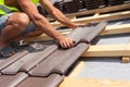 Hands of roofer laying tile on the roof. Installing natural red tile