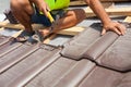 Hands of roofer laying tile on the roof. Installing natural red tile