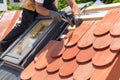 Hands of roofer laying tile on the roof. Installing natural red tile using hammer.