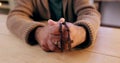 Hands, rosary and cross with closeup for religion, peace and hope at desk, home or praying for worship. Person, crucifix