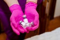 Hands in rubber gloves hold glass ampoules with medicines