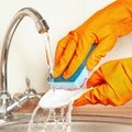 Hands in rubber gloves with sponge wash dirty dishes under running water Royalty Free Stock Photo