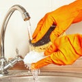 Hands in rubber gloves with sponge wash dirty plate under running water Royalty Free Stock Photo