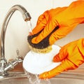 Hands in rubber gloves with sponge wash dishes under running water Royalty Free Stock Photo