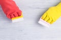 Hands in rubber yellow and red gloves washed with brushes light gray wooden floor Royalty Free Stock Photo