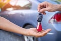 The hands of a salesman are sending car keys intended for sale-lease to a customer or new owner.