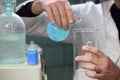 Hands of a scientist pouring a reagent into a flask