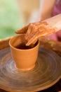 Hands sculpts cup from clay pot. Workshop of modeling on potter wheel Royalty Free Stock Photo