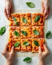 Hands selecting roman style pizza slices from a small rectangular pie on a bright white background Royalty Free Stock Photo