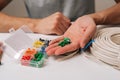 Hands selecting wire ferrules from plastic organizer next to coiled electrical cable on white table, depicting diy, home Royalty Free Stock Photo