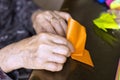 Hands of senior lady folding Origami paper