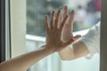 Hands separated by a glass window for social distancing during the corona virus lockdown Royalty Free Stock Photo