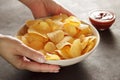 Hands serving bowl with potato chips on table with dip sauce. Royalty Free Stock Photo