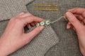 Hands Sewing Buttons onto Crocheted Gray Fabric