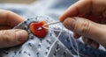 Hands sewing a red heart button Royalty Free Stock Photo