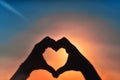 Hands in the shape of a heart against sunlight in the sunset sky, dusk. Symbol of love Royalty Free Stock Photo