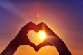 Hands in the shape of a heart against sunlight in the sunset sky, dusk. Symbol of love Royalty Free Stock Photo