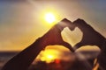 Hands in the shape of a heart against sunlight in the sunset sky, dusk. Symbol of love Royalty Free Stock Photo