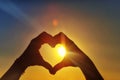 Hands in the shape of a heart against sunlight in the sunset sky, dusk. Symbol of love Royalty Free Stock Photo