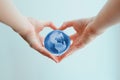 Hands in shape of heart holding blue glass globe of South and North America Royalty Free Stock Photo