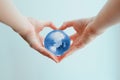 Hands in shape of heart holding blue glass globe of South Pole