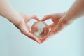Hands in shape of heart holding glass globe of South Pole