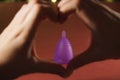 Hands in the shape of a heart and a menstrual Cup. zero weist, the trend for environmental friendliness and safety for women`s