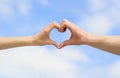 Hands in shape of love heart. Heart from hands on a sky background. Love, friendship concept. Girl and male hand in Royalty Free Stock Photo