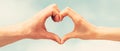 Hands in shape of love heart. Heart from hands on a sky background. Love, friendship concept. Girl and male hand in Royalty Free Stock Photo