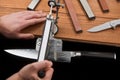 Hands sharpening a Japanese knife with Damascus steel using a manual machine