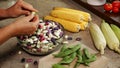 Hands shelling fresh colorful beans into glass bowl