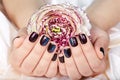 Hands with short manicured nails colored with dark purple nail polish and flower Royalty Free Stock Photo