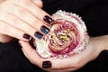 Hands with short manicured nails colored with dark purple nail polish holding a flower Royalty Free Stock Photo