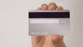 Hands is show back of silver credit card on white background